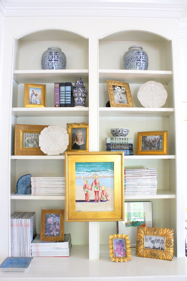 This beautiful bookcase is styled with family pictures with matching gold colored frames and stacks of magazines