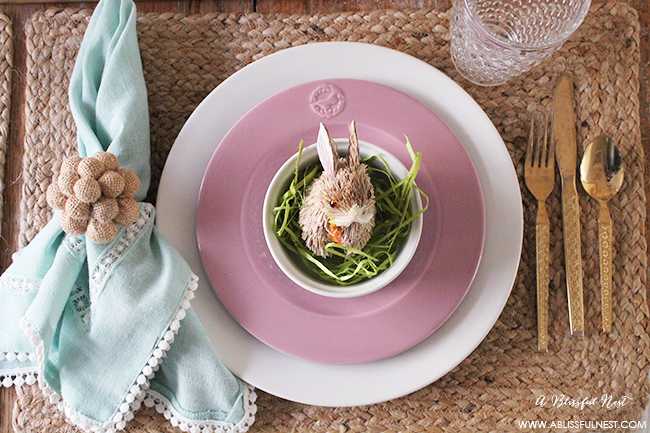A beautiful and soft Easter table decor setting that is the perfect transition into spring. Soft whites with pops of flowers and pastels makes this Easter table setting perfect for your family! Check out more of this table on ablisfulnest.com