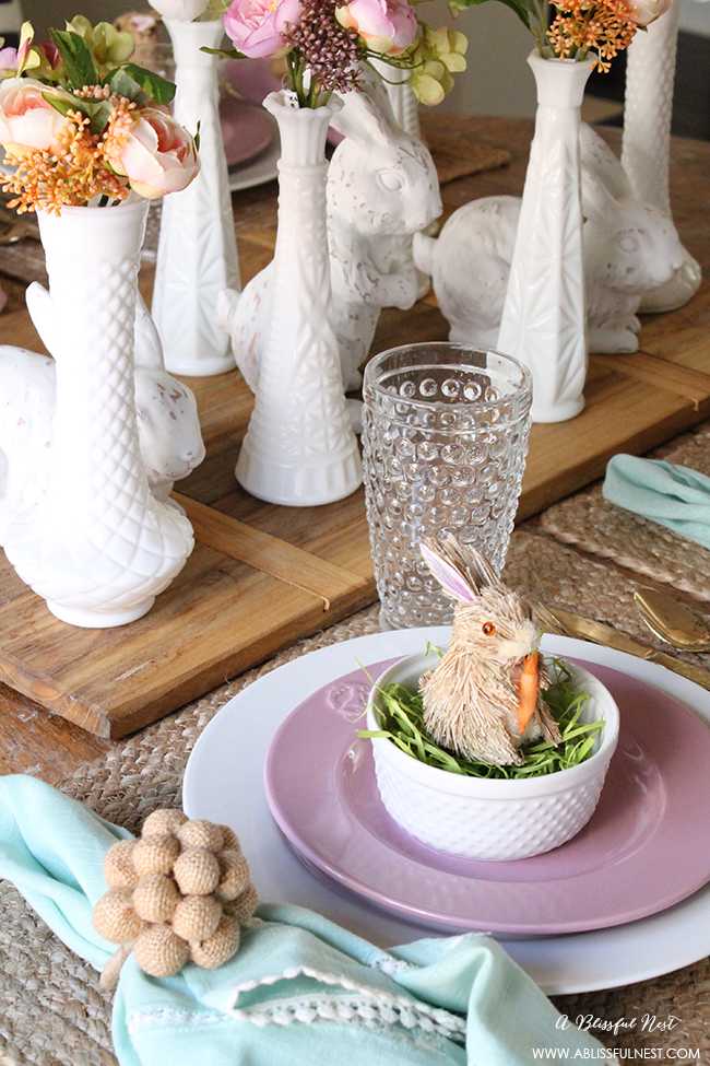 A beautiful and soft Easter table decor setting that is the perfect transition into spring. Soft whites with pops of flowers and pastels makes this Easter table setting perfect for your family! Check out more of this table on ablisfulnest.com