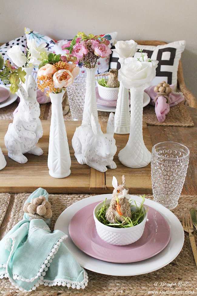 A beautiful and soft Easter table decor setting that is the perfect transition into spring. Soft whites with pops of flowers and pastels makes this Easter table setting perfect for your family! Check out more of this table on ablisfulnest.com