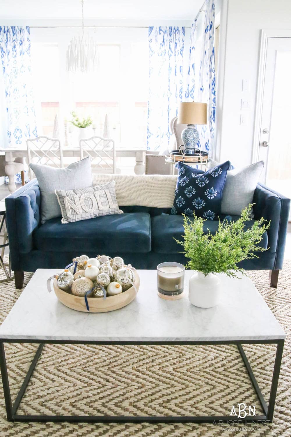 Beautiful blue and silver Christmas living room decor in a bright white space with juniper garland and silver and blush ornaments. Check out all the white, silver and gold Christmas decor in this holiday home tour on ablisfulnest.com. #ABlissfulNest #Christmasdecor #Christmasdecorating #CoastalChristmasdecor #christmastree #christmasmantle
