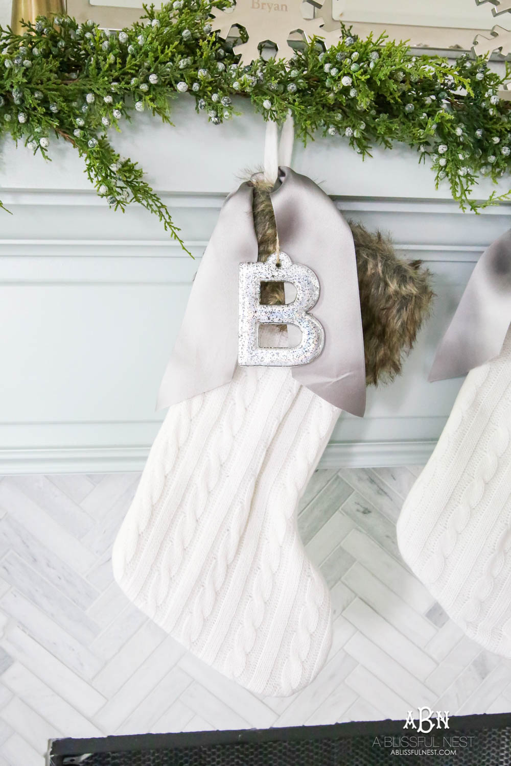 Gorgeous blue and silver Christmas mantle décor with juniper berry garland and glass hurricane Christmas trees. Simple and festive holiday décor in this open concept living space. Check out all the white, silver and gold Christmas decor in this holiday home tour on ablisfulnest.com. #ABlissfulNest #Christmasdecor #Christmasdecorating #CoastalChristmasdecor #christmastree #christmasmantle