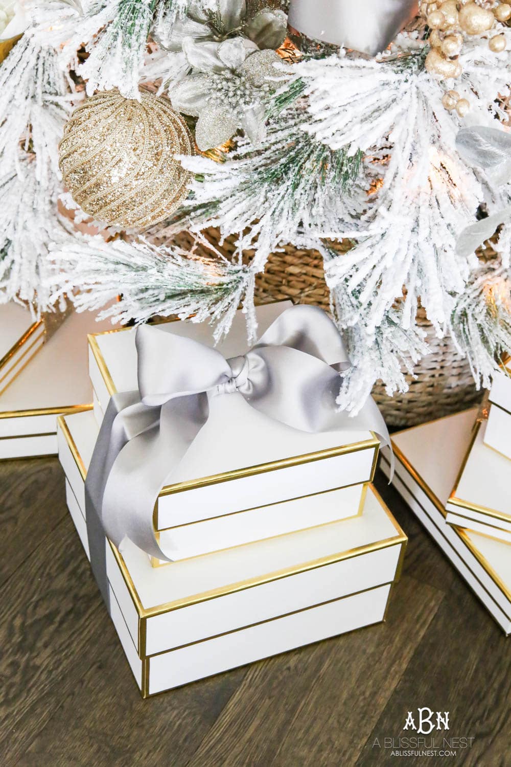 White boxes with gold trim make the perfect wrapping for gifts under this white flocked tree with silver and gold accents. Check out all the white, silver and gold Christmas decor in this holiday home tour on ablisfulnest.com. #ABlissfulNest #Christmasdecor #Christmasdecorating #CoastalChristmasdecor #christmastree