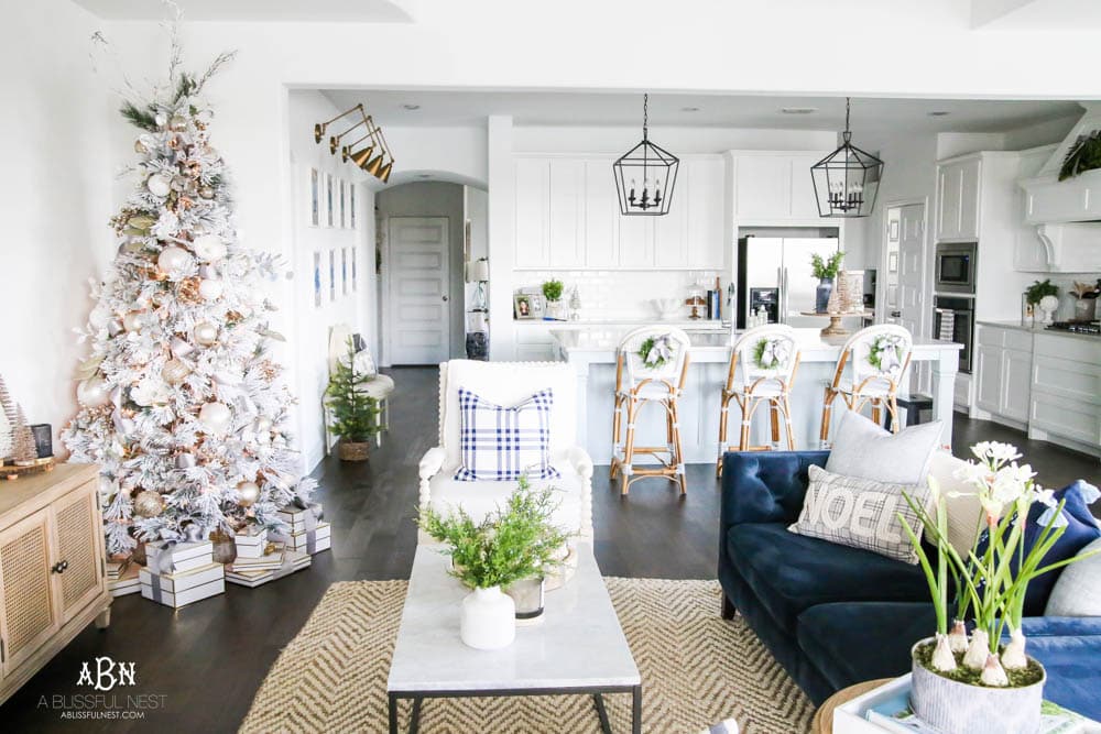 Beautiful blue and silver Christmas living room decor in a bright white space with juniper garland and silver and blush ornaments. Check out all the white, silver and gold Christmas decor in this holiday home tour on ablisfulnest.com. #ABlissfulNest #Christmasdecor #Christmasdecorating #CoastalChristmasdecor