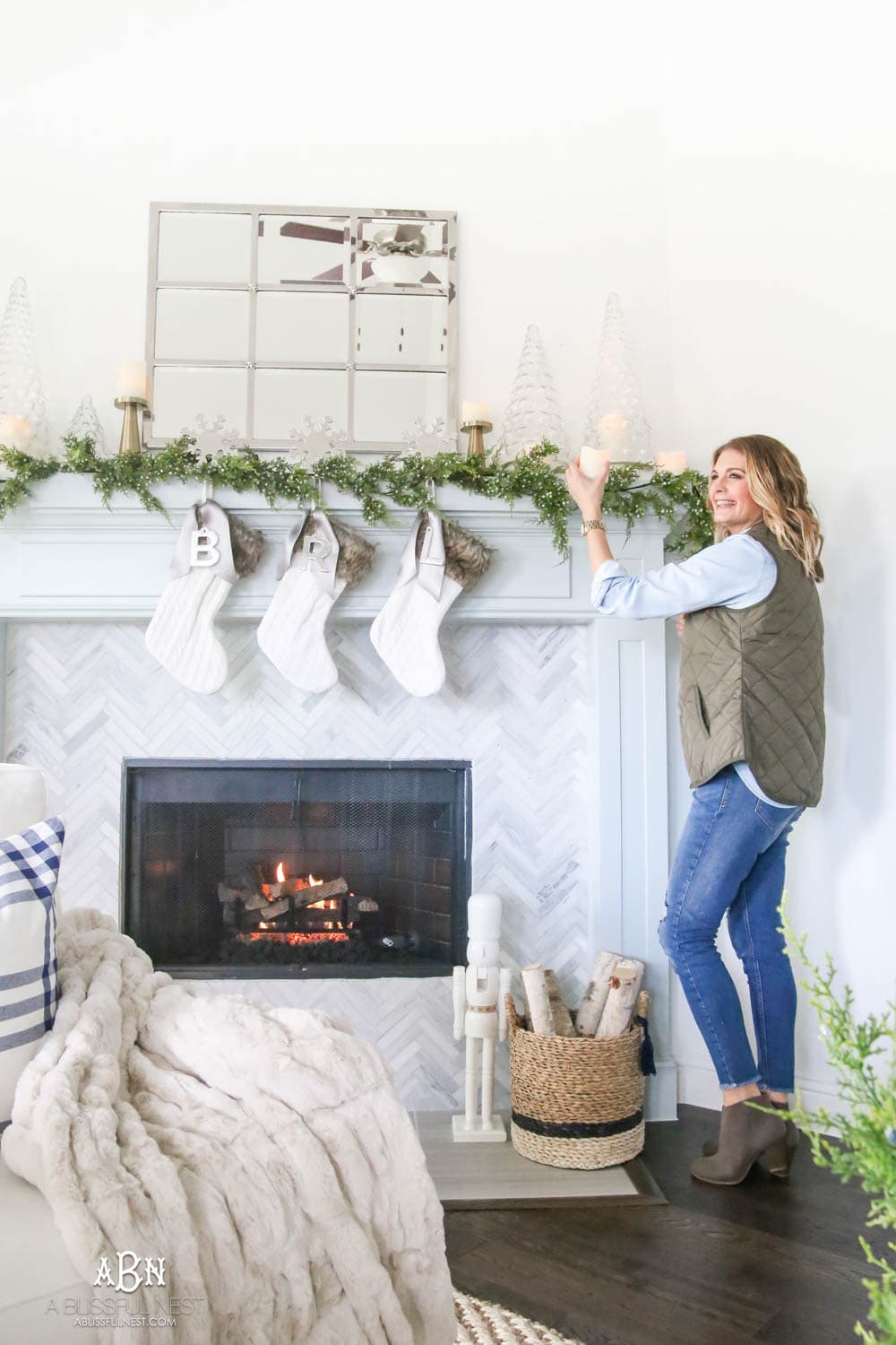 Gorgeous blue and silver Christmas mantle décor with juniper berry garland and glass hurricane Christmas trees. Simple and festive holiday décor in this open concept living space. Check out all the white, silver and gold Christmas decor in this holiday home tour on ablisfulnest.com. #ABlissfulNest #Christmasdecor #Christmasdecorating #CoastalChristmasdecor #christmastree #christmasmantle