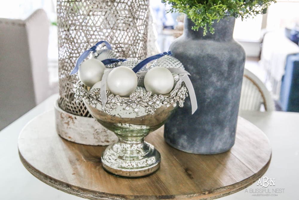 Blue and silver Christmas kitchen décor. All white kitchen with subtle holiday décor for a fresh coastal Christmas look. Mini wreaths on the backs of the barstools, beautiful bay leaf above the range. #christmaskitchen #christmashometour #holidayhometour #kitchenideas