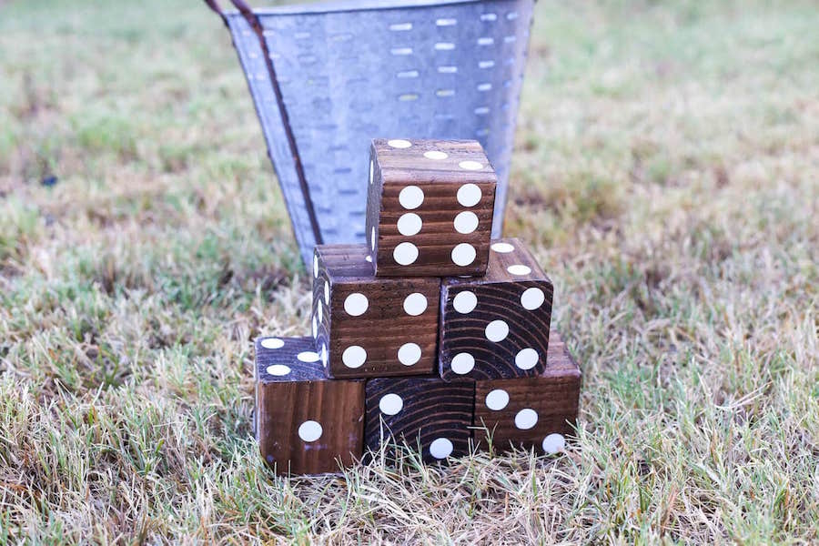 6 large wood dice in the grass with a metal bucket behind them
