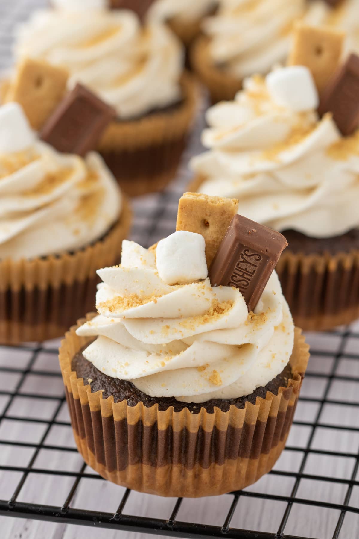 Cupcakes with smooth buttercream frosting, gold sprinkles, piece of Hershey chocolate and graham cracker. 