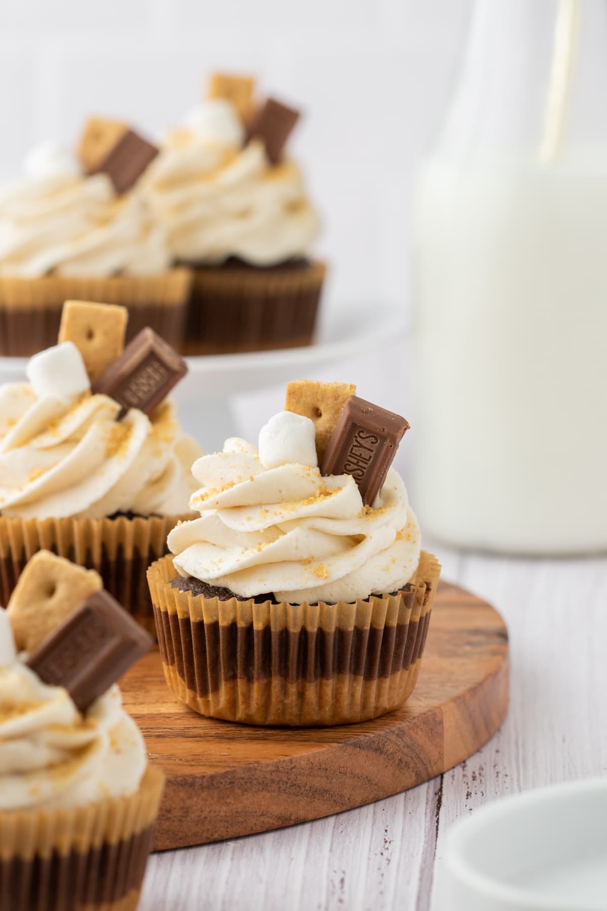 Cupcakes with smooth buttercream frosting, gold sprinkles, piece of Hershey chocolate and graham cracker. 