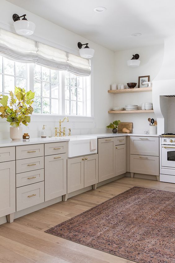 Beige kitchen cabinets with a area rug that is in shades of browns and deep red browns. 