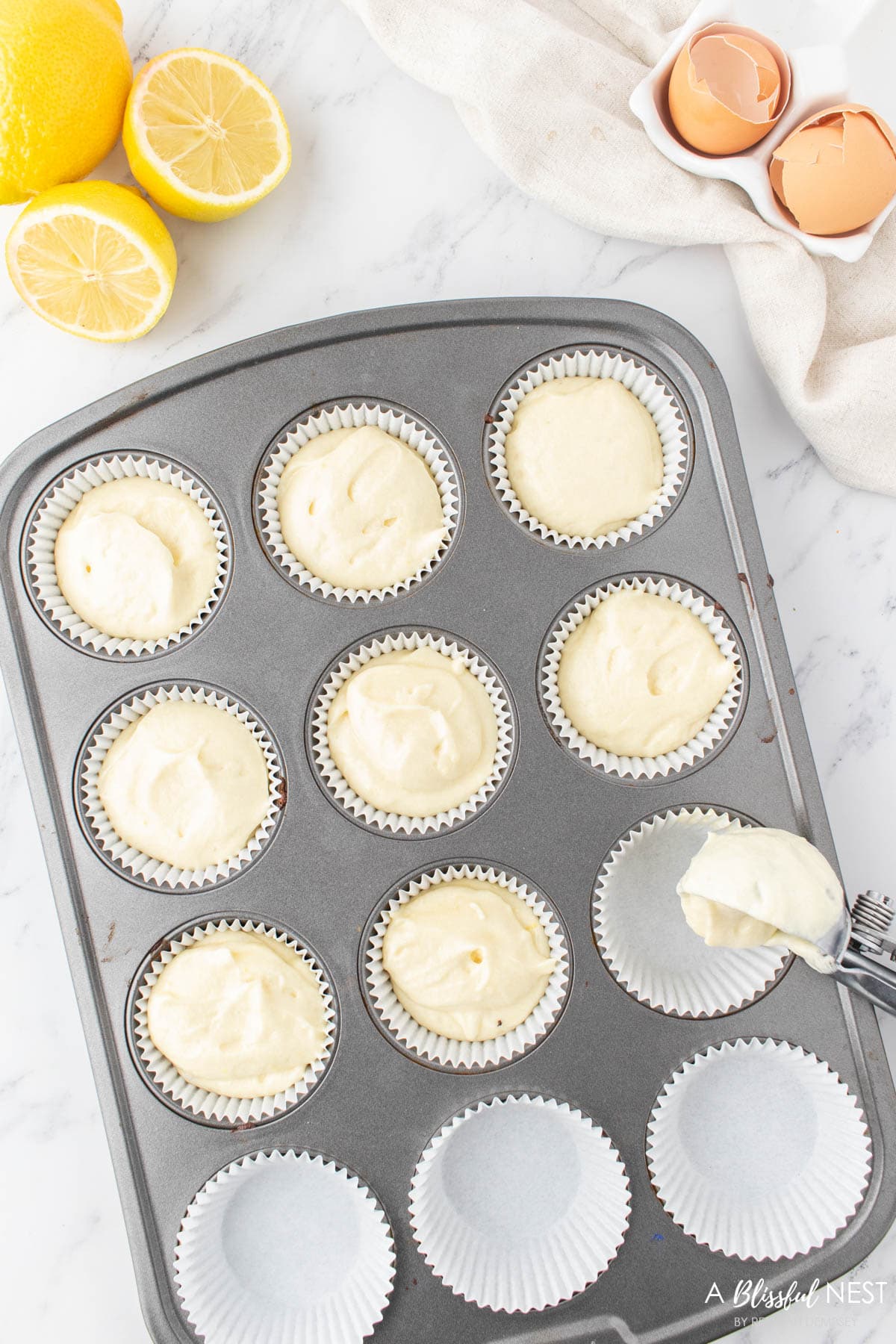 Cupcake pan with liners being filled with cupcake batter.