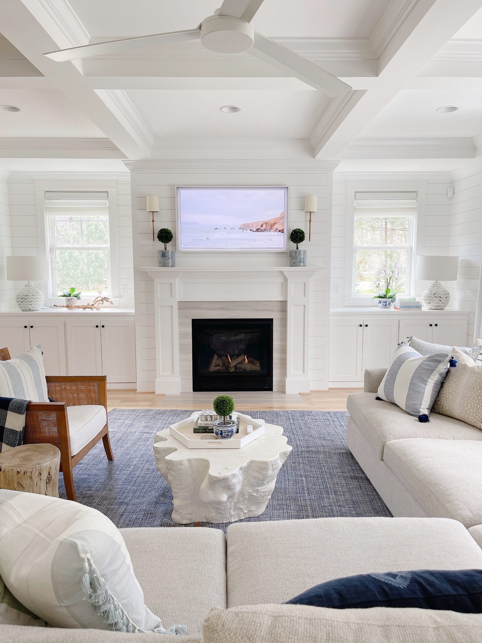 white fireplace mantel with 2 small boxwood topiaries in blue and white pots.