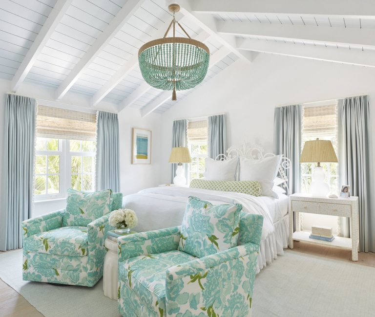 All white bedroom mixed with a turquoise beaded chandelier and 2 floral print chairs with light grey curtains