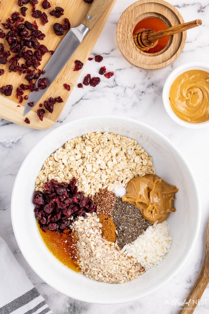 white bowl on countertop with each of the ingredients added to it to make the energy balls.
