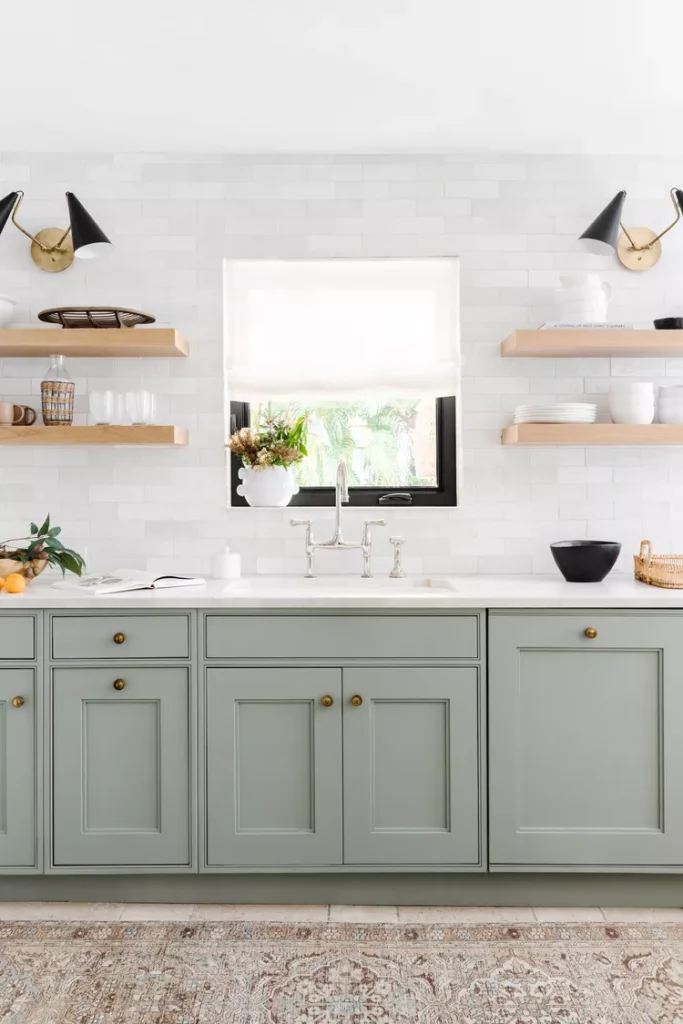 seafoam green cabinets with white quartz countertops. Wood floating shelves. 