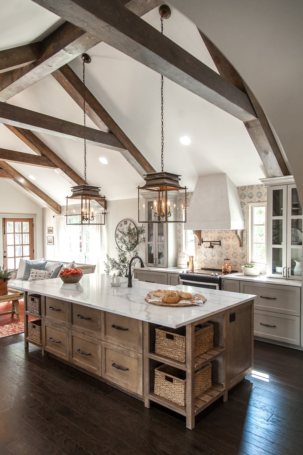 natural wood kitchen island with quartz countertops, grey kitchen cabinets, black cabinet hardware, lantern pendant lights over island.