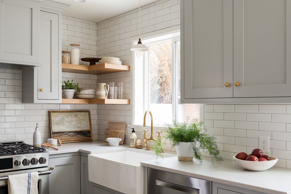 light grey kitchen cabinets in this small kitchen design with gold hardware and wood floating shelves