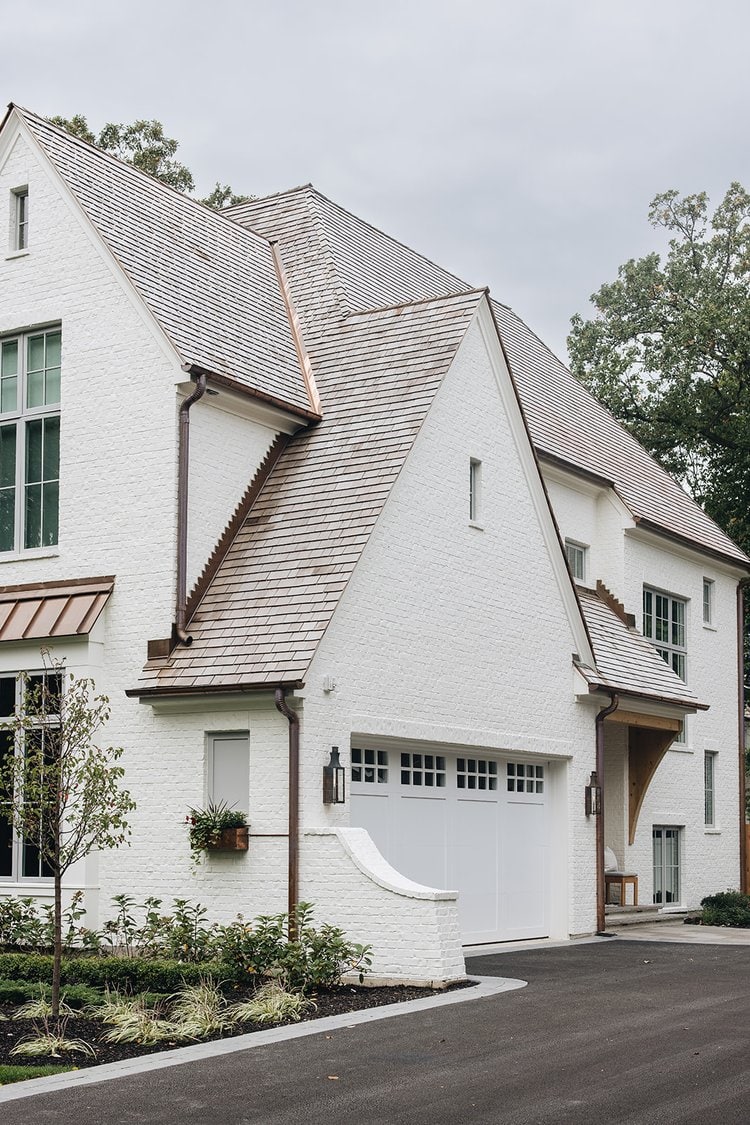Creamy white painted bricks for the exterior of this home with soft light gray painted garage doors.