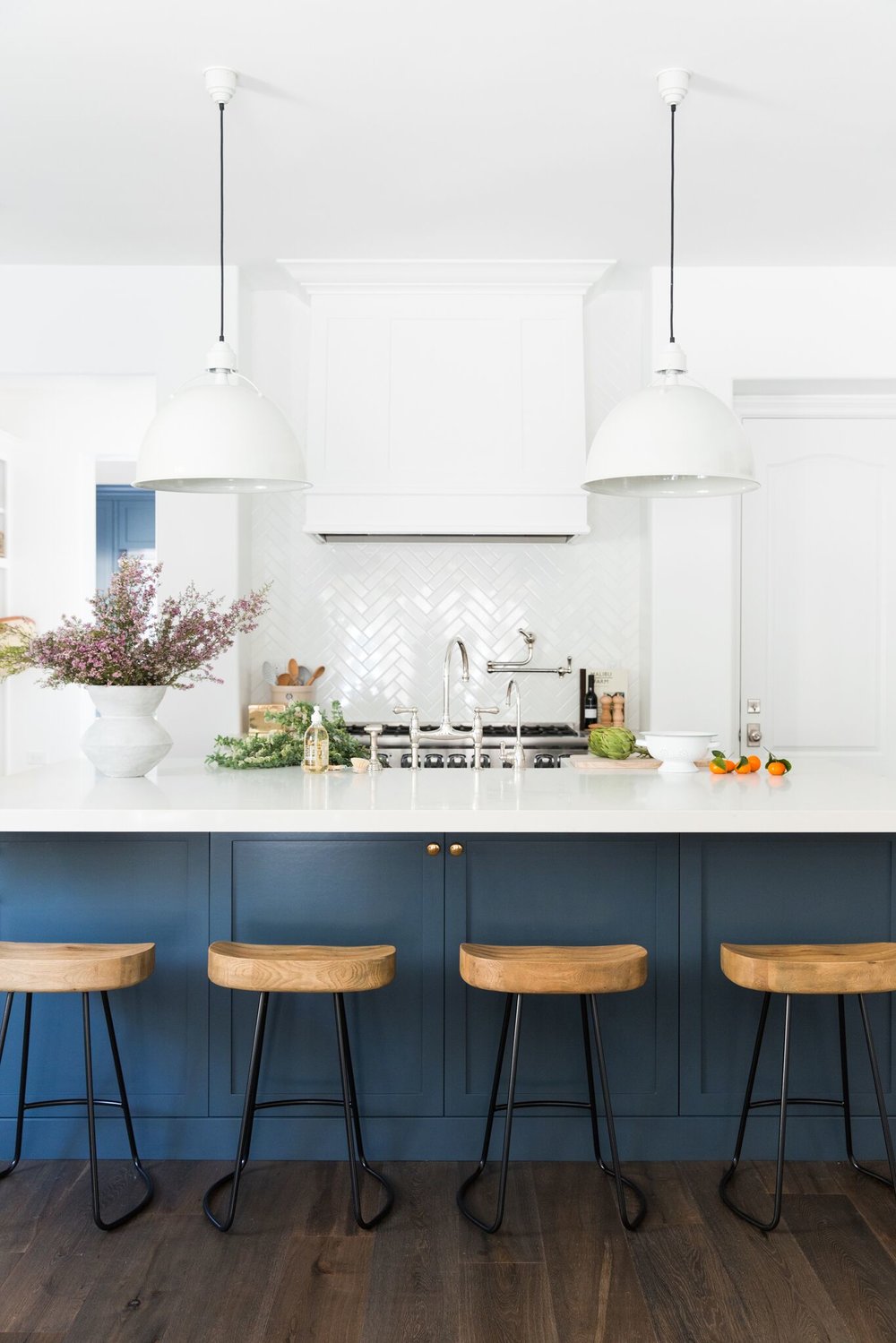 navy kitchen island with industrial wood barstools, white range hood