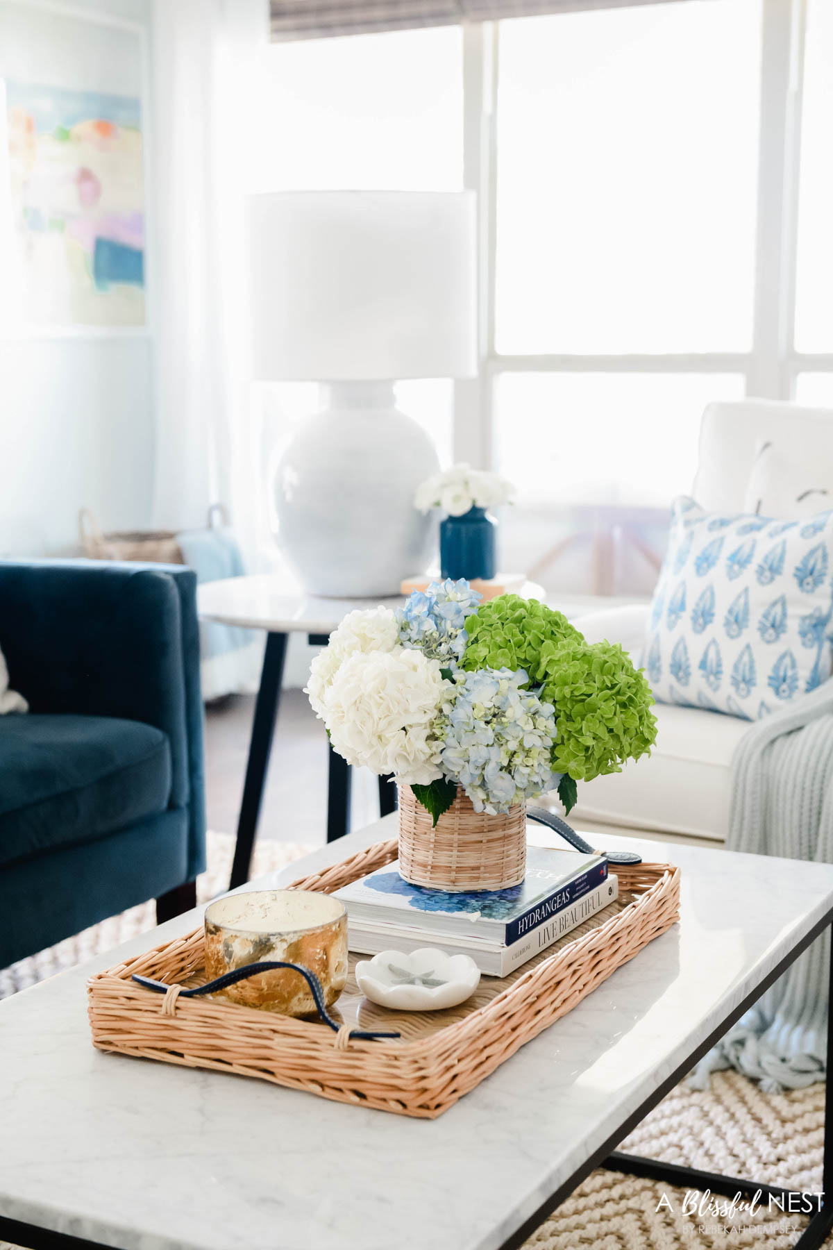 marble topped coffee table with metal legs, rattan tray with vase of hydrangeas. 