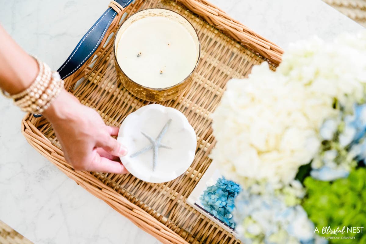small marble tray on a rattan tray being used to decorate a coffee table.