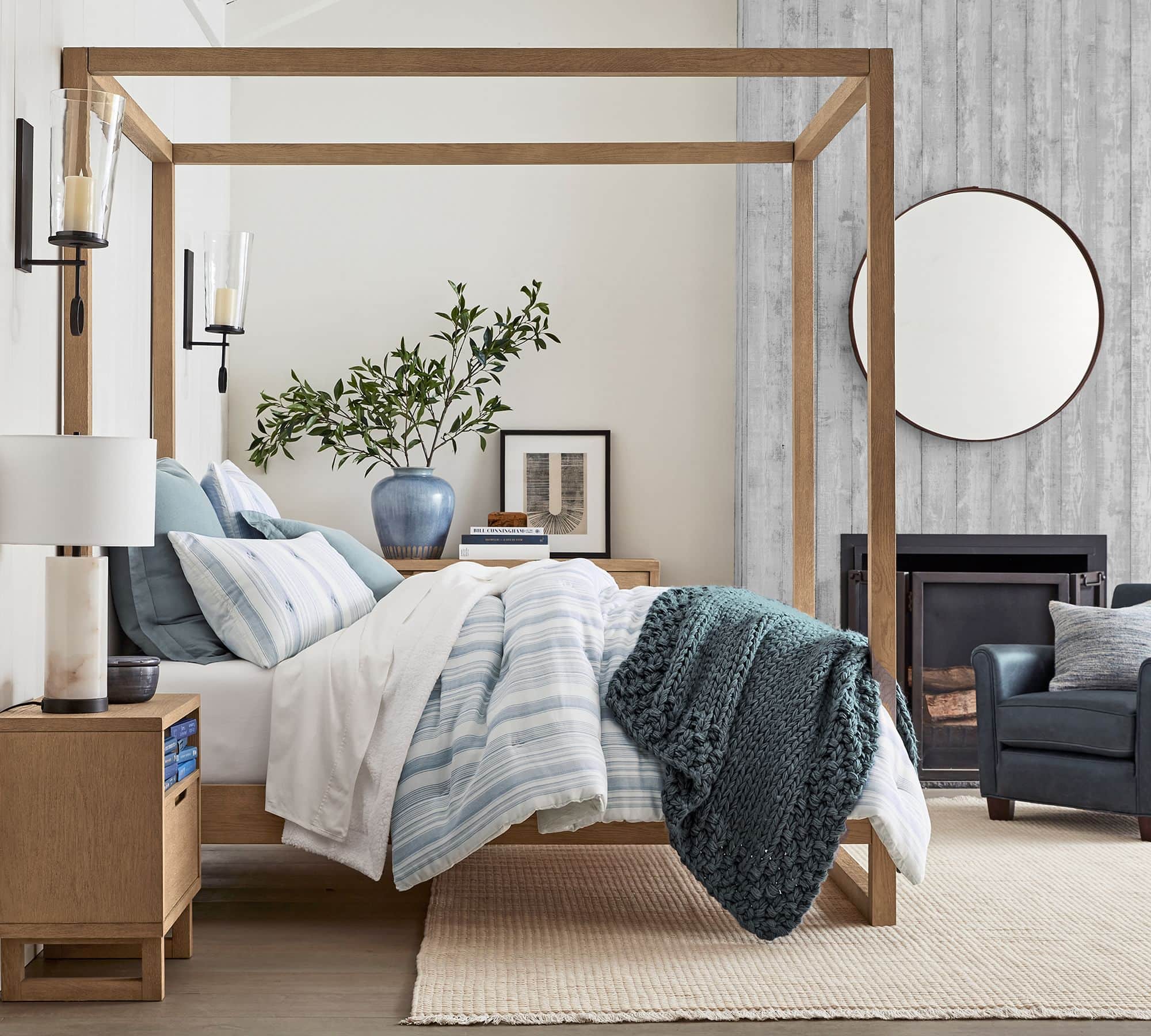 blue and white stripe bedding with a chunky knit throw blanket in a dark green blue at the end of the bed