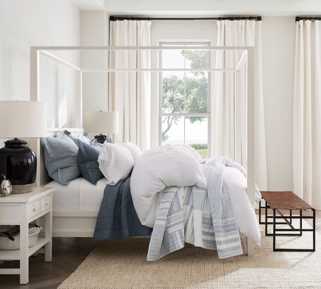 navy quilt and shams with light blue duvet on a white frame bed