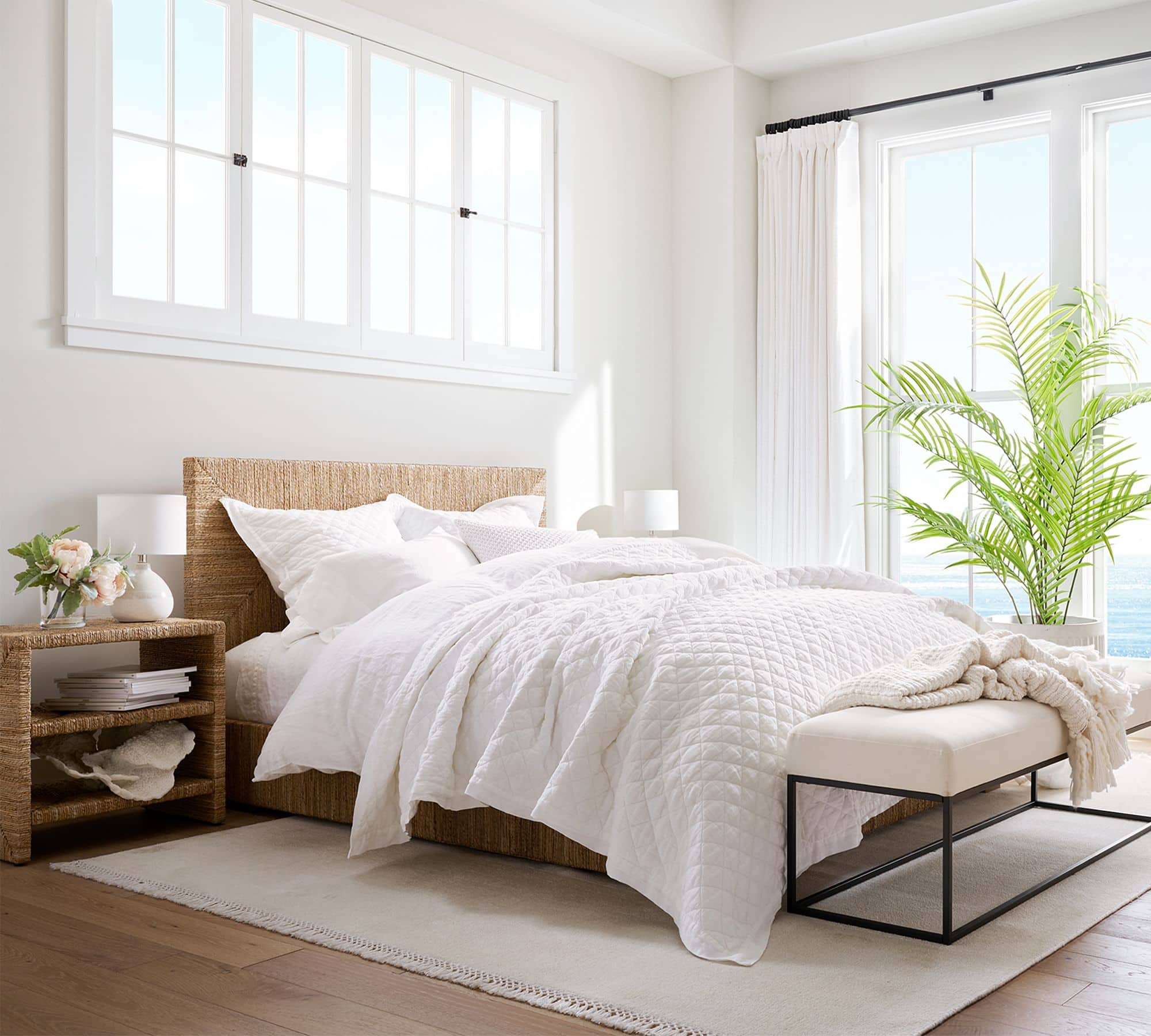 white quilt with white bedding. sea grass nightstand and headboard