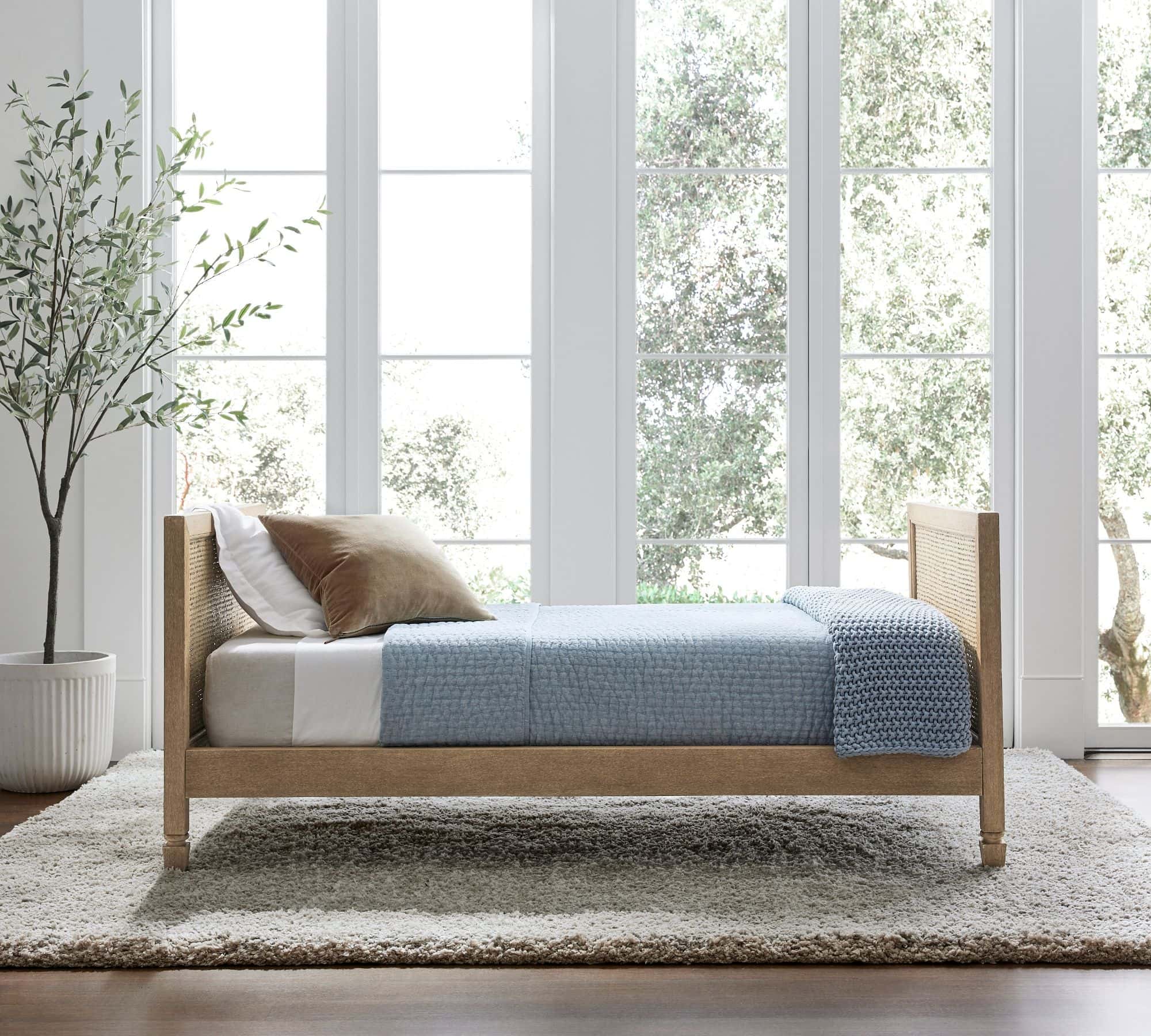 light blue quilt tucked in on sides with white bedding, brown velvet pillow