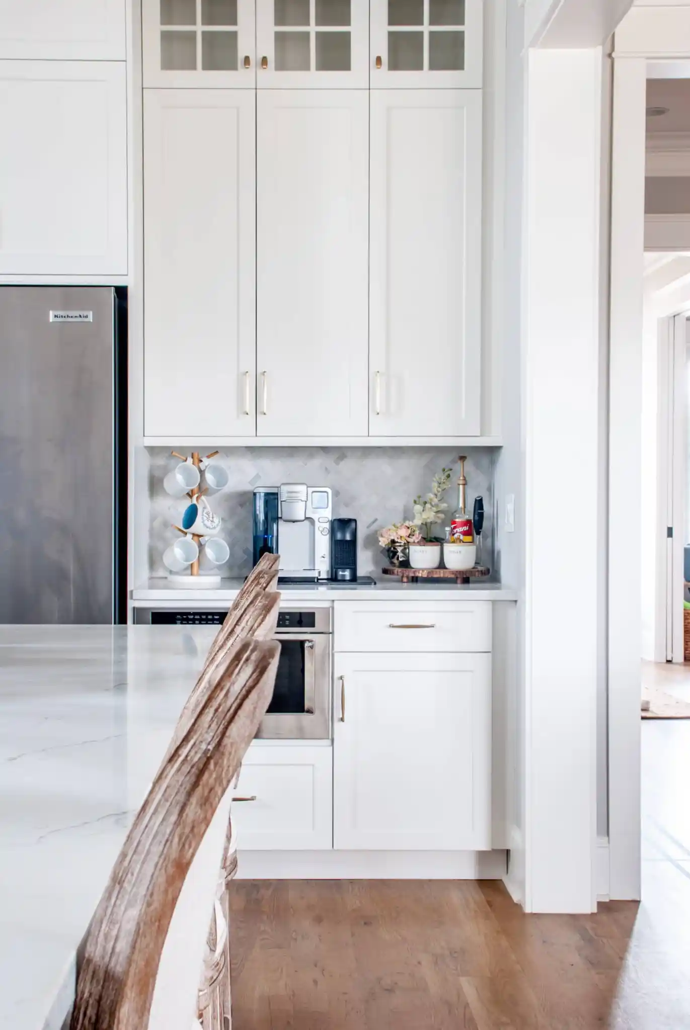 a coffee machine with a side tray with coffee ingredients and a tiered mug rack on a counter in a kitchen.