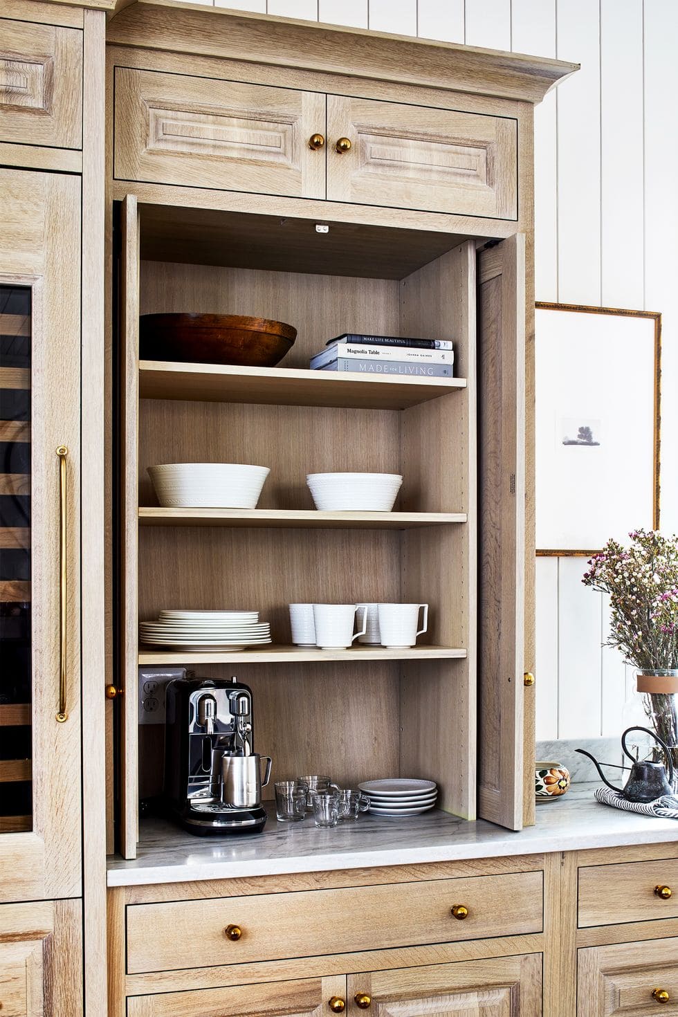 Closed cabinet coffee station with white mugs and plates.