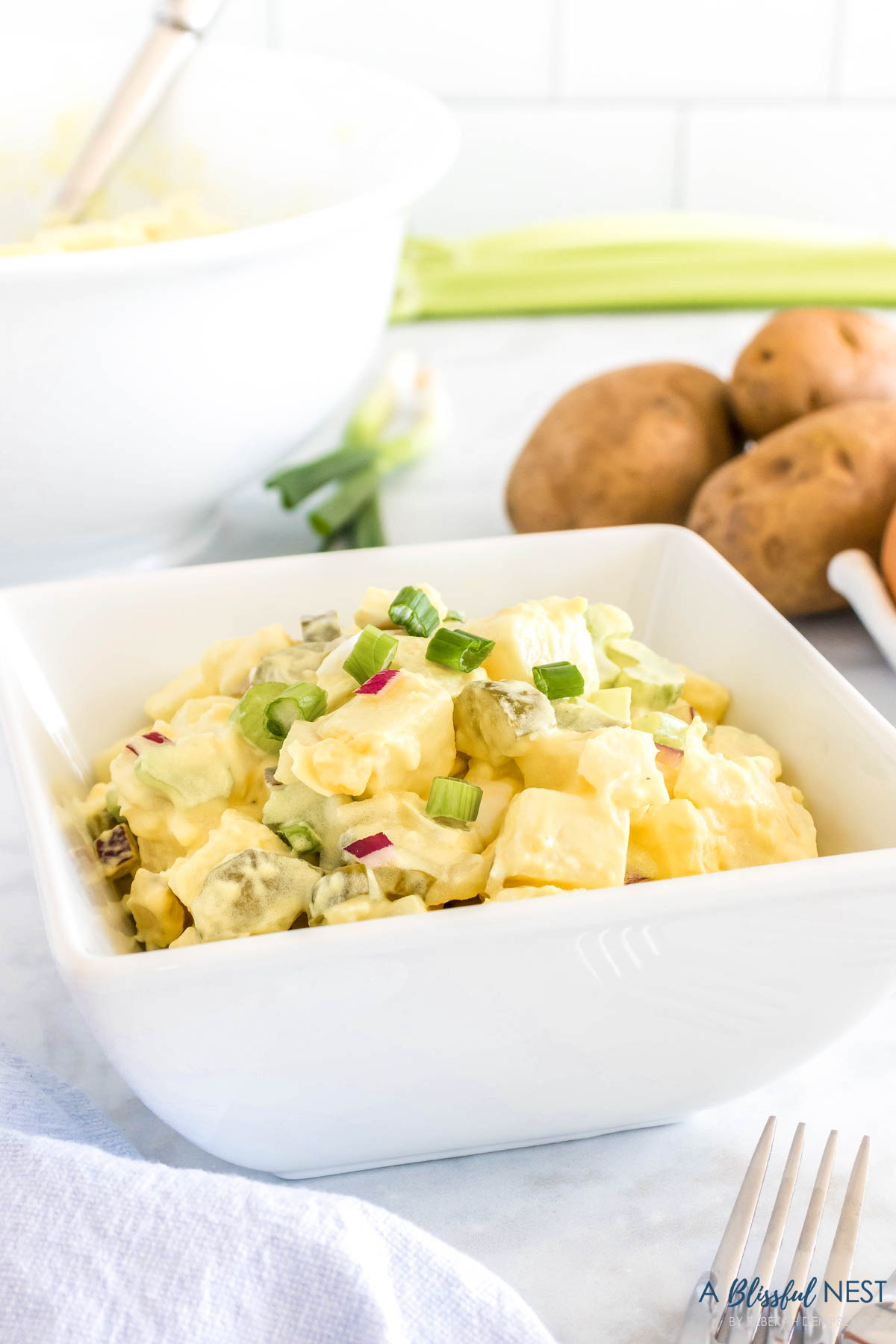 white bowl filled with potato salad as a side dish on a counter.