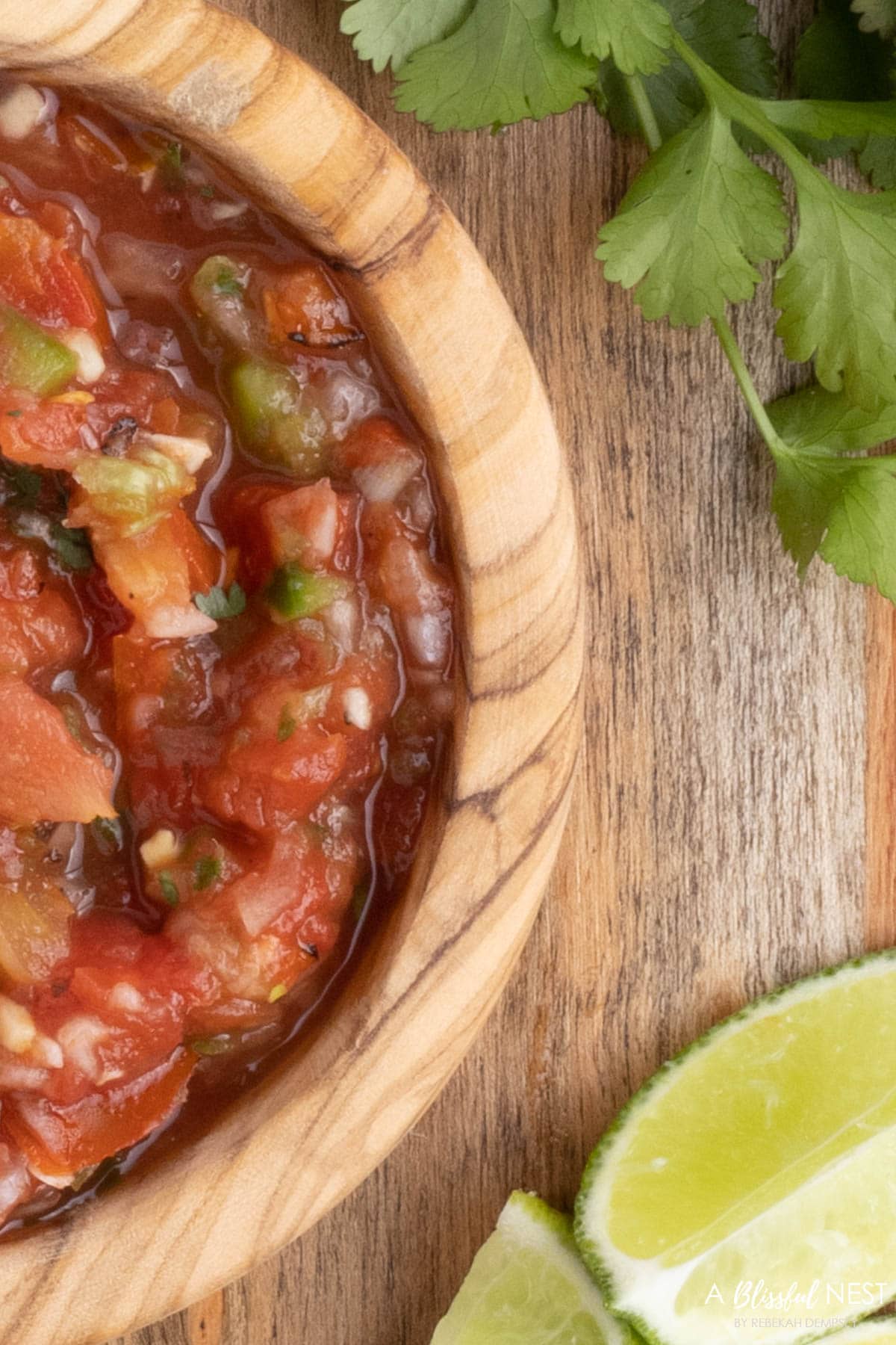 wood bowl with salsa with a cut lime next to it.
