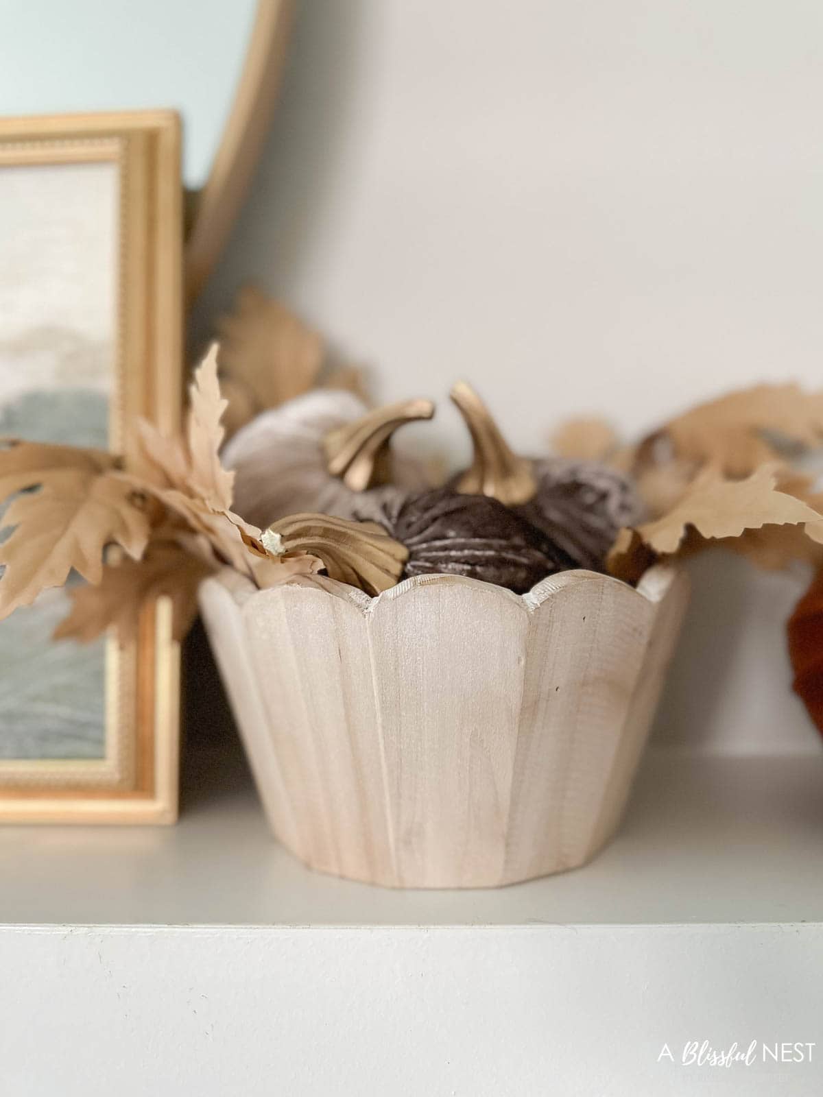 wood scalloped bowl filled with mini velvet pumpkins.