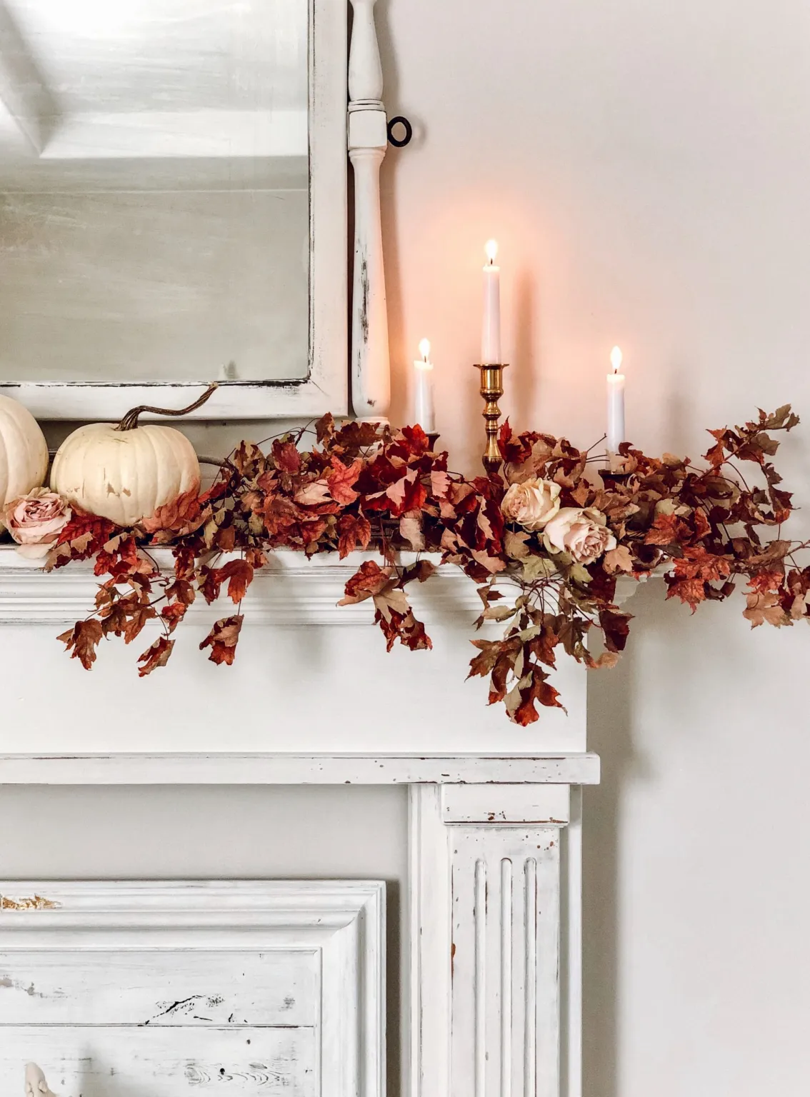 vintage mantel with amber colored dried foliage and pumpkins on top