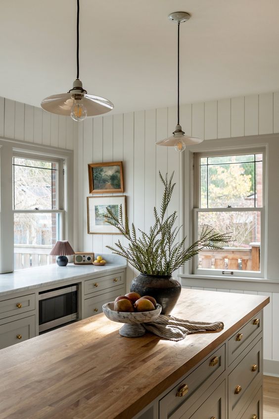 butcher block countertop with sage green cabinets and gold cabinet hardware