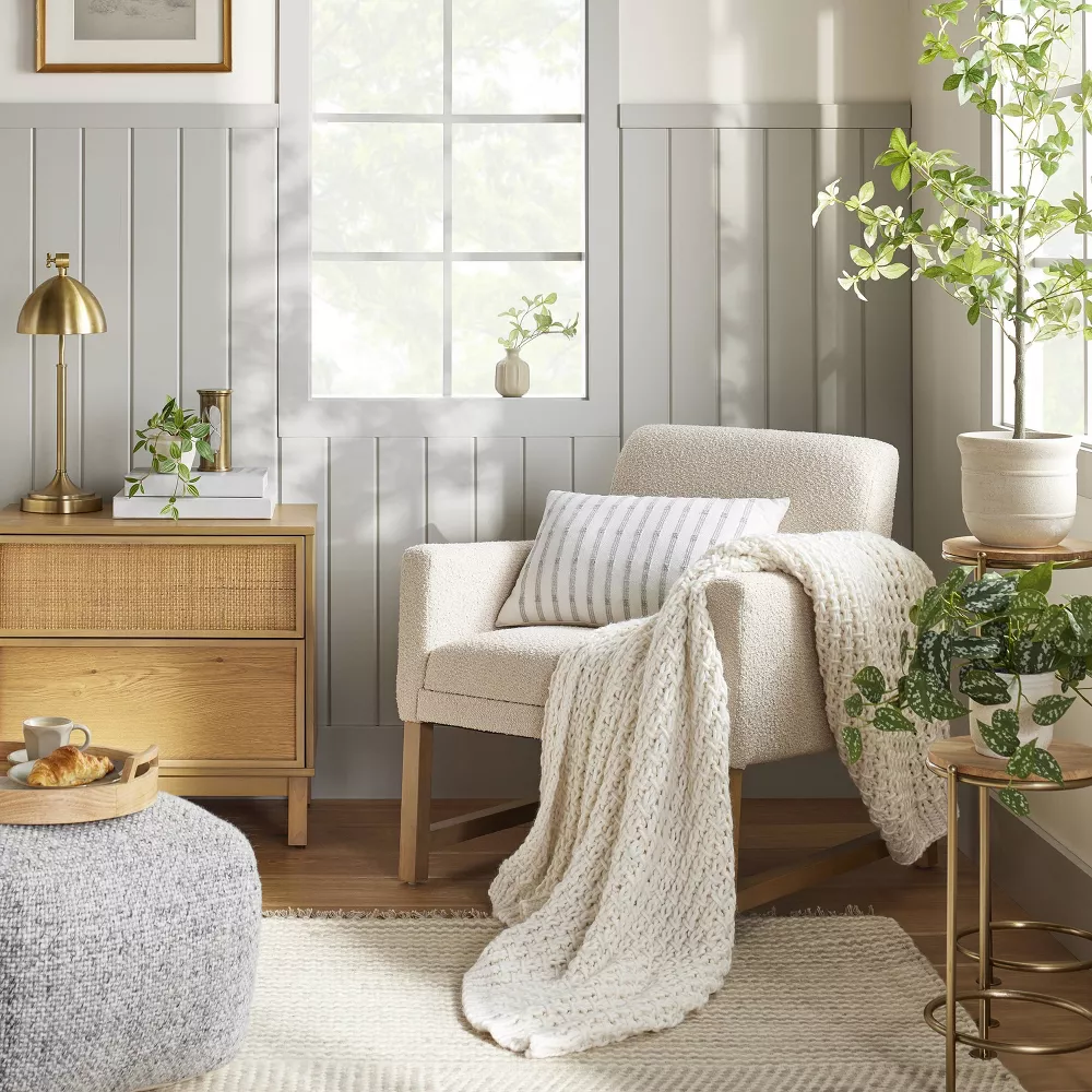 Soft gray vertical shiplap walls with a chair in the corner and a rattan cabinet next to it.
