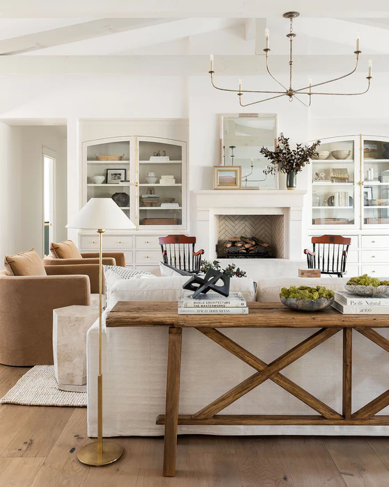 neutral living room with a wood x base farmhouse console table behind a sofa
