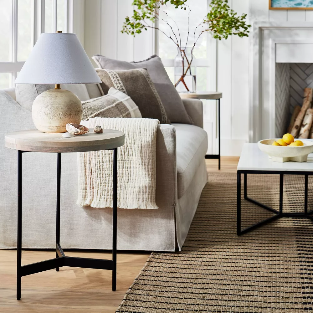 wood top side table with black iron base in a living room setting