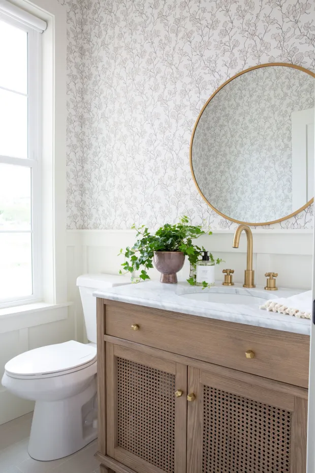 cane door fronts on this wood cabinet with marble countertop in this farmhouse bathroom