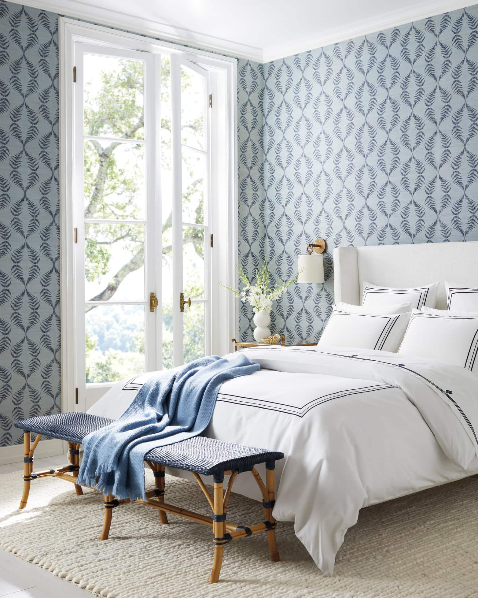 light and navy blue patterned wallpaper with white bedding that has a blue band on it.