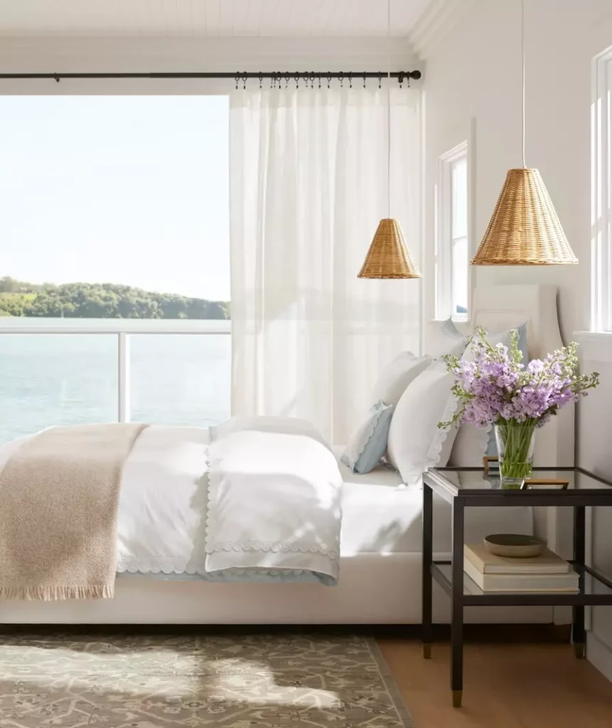 white bedding layered with beige and light blue accent bedding pieces.