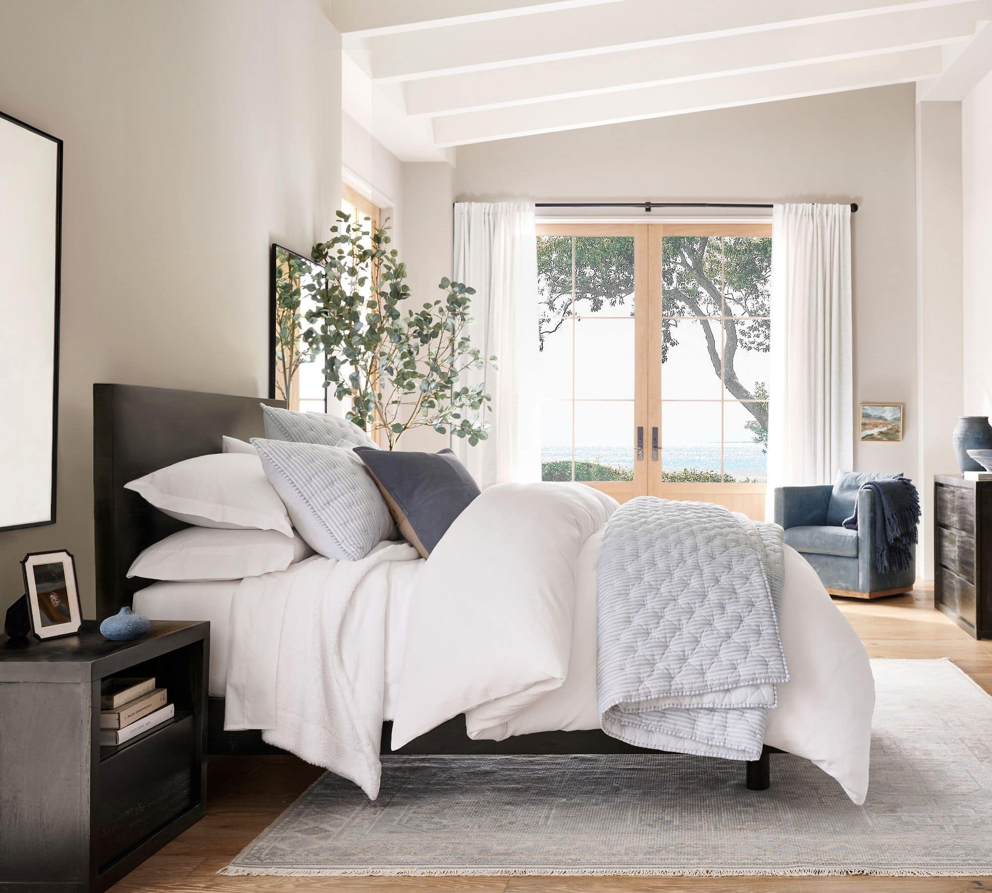 white bedding layered with ticking stripe blanket and shames