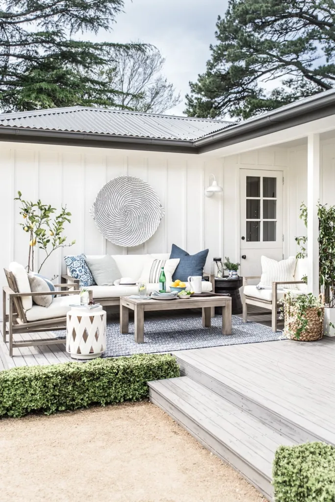 small patio space with seating arrangement with small landscaping details like boxwood border, potted trees.