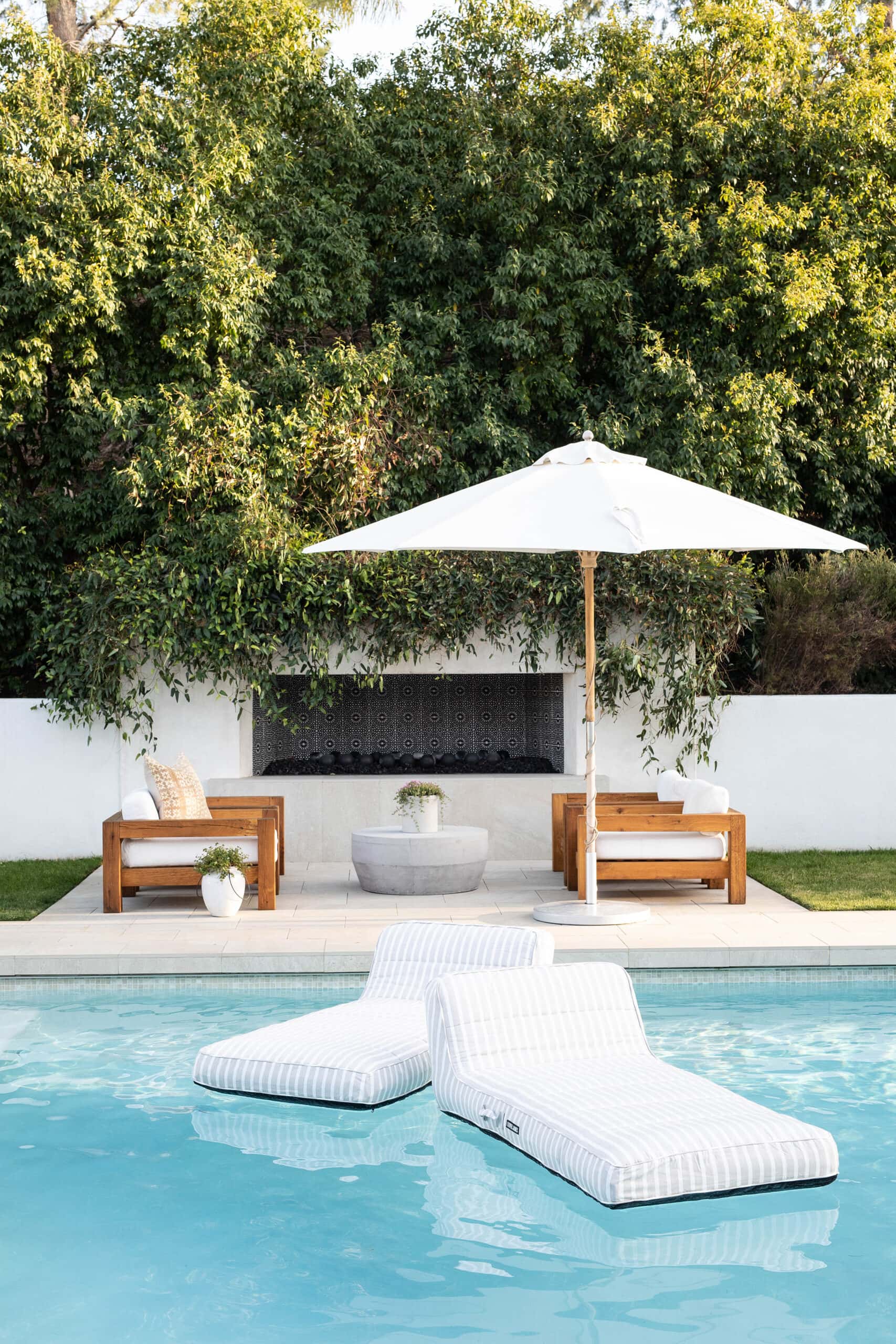 modern backyard with sleek teak furniture in front of an out door tiled fireplace.