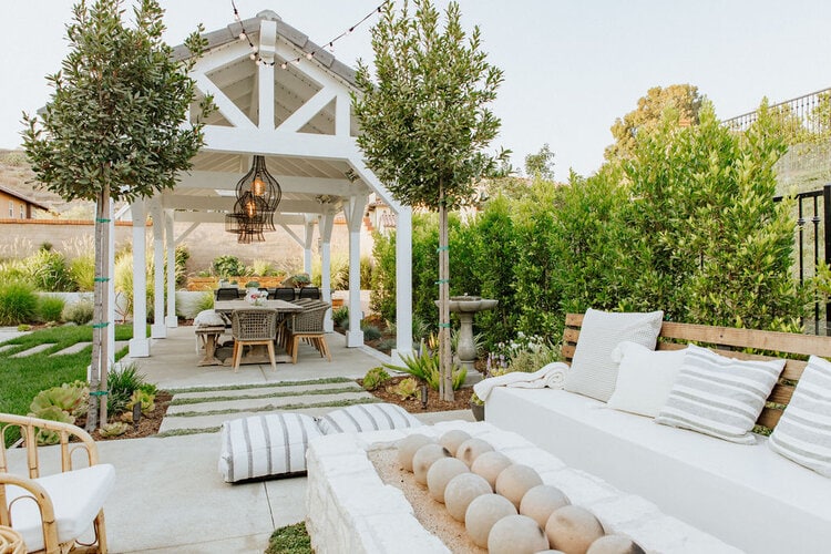 dining area under a pitched pergola with hanging lanterns